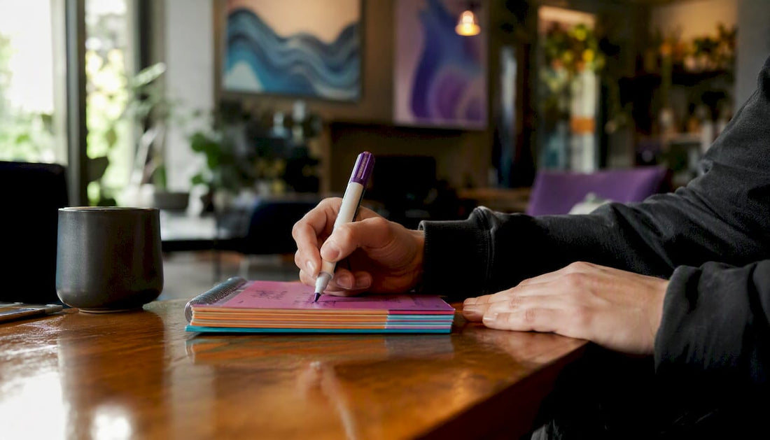 Hands writing lyrics in notebook on table