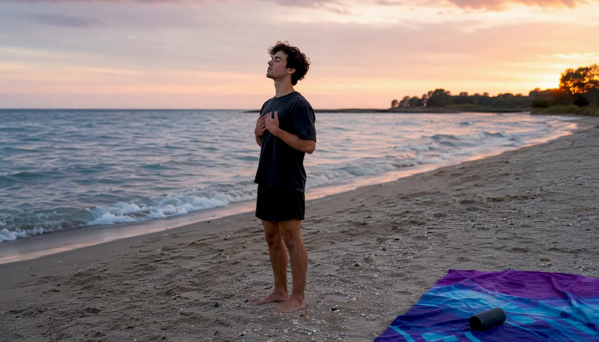 Person practicing breathing by lake at dawn