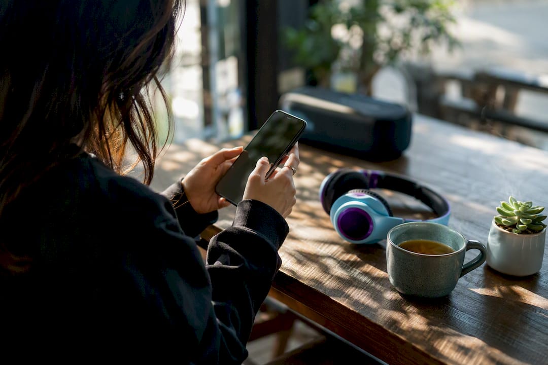 Hands selecting songs on smartphone playlist