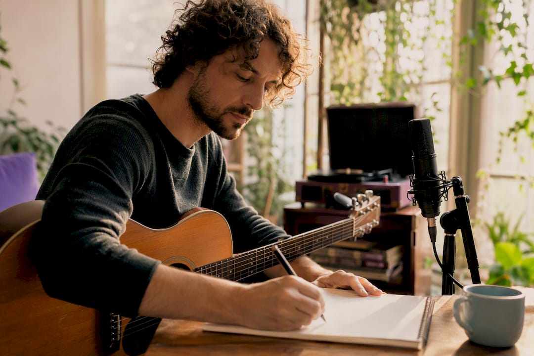 Musician writing and playing guitar