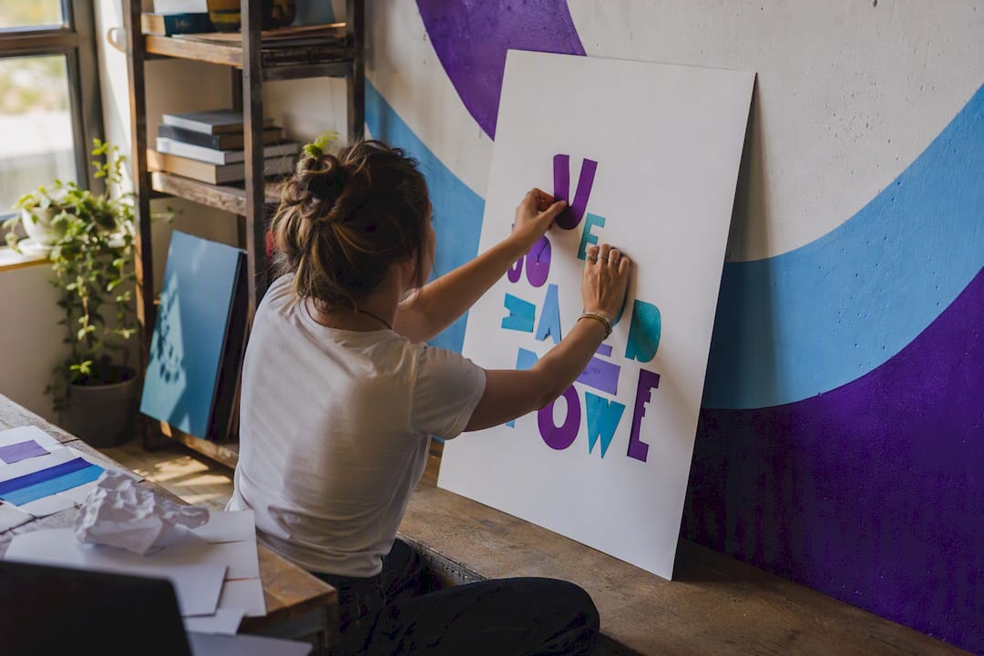 Hands arranging letters on motivational poster